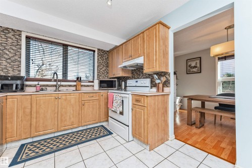 Kitchen featuring light wood cabinetry, a mosaic tile backsplash, and white appliances - 49 Ash Crescent, St. Albert, AB - Indoor Photo Showing Kitchen