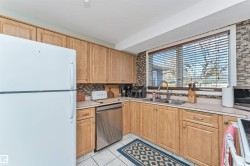 Kitchen featuring light wood-finish cabinetry, a stainless steel dishwasher, and a double basin sink - 