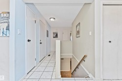 Hallway featuring square tile flooring and white trim - 