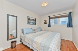 Bedroom featuring wood-finish flooring, a double window with blinds, and a flush-mount ceiling light fixture - 