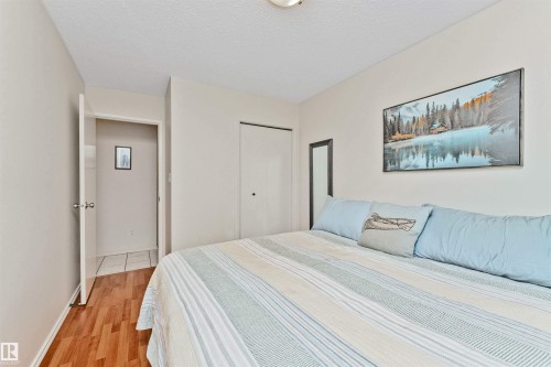 Bedroom featuring wood-finish flooring, neutral wall tones, and a built-in closet with bi-fold doors - 49 Ash Crescent, St. Albert, AB - Indoor Photo Showing Bedroom
