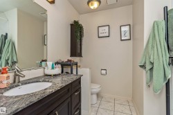 Bathroom featuring a dark wood-finish vanity with an undermount sink, a stone-finish countertop, and a large wall-mounted mirror - 