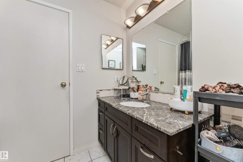 Vanity featuring a dark wood-finish base cabinet, an integrated sink, and a stone-finish countertop - 49 Ash Crescent, St. Albert, AB - Indoor Photo Showing Bathroom