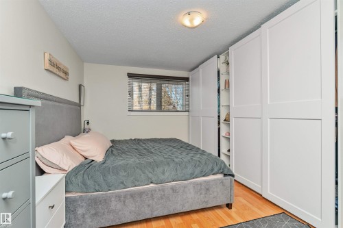 Bright interior space featuring wood-finish flooring, a window with blinds, and built-in closet storage - 49 Ash Crescent, St. Albert, AB - Indoor Photo Showing Bedroom