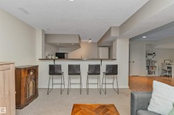 Lower-level recreation space featuring a wet bar with wood-finish countertop, recessed lighting, and soft carpet flooring - 