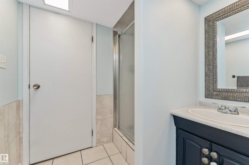 Bathroom featuring a dark wood-finish vanity with an integrated sink, framed mirror, and a shower enclosure with frosted glass - 49 Ash Crescent, St. Albert, AB - Indoor Photo Showing Bathroom