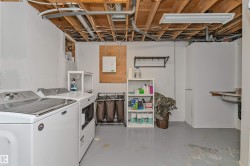 Laundry area featuring a side-by-side washer and dryer, exposed ceiling joists and utilities, a utility sink, and painted concrete flooring - 