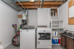 Utility space featuring an exposed ceiling, light gray flooring, and white painted walls - 
