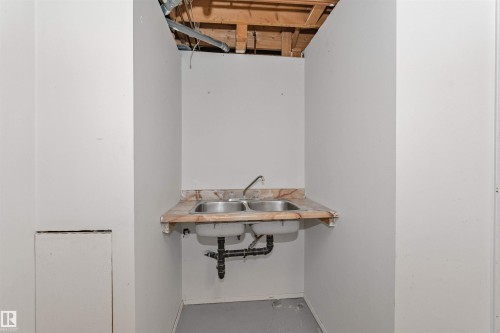 Utility sink area featuring a dual stainless steel sink, a patterned countertop, and exposed overhead joists - 49 Ash Crescent, St. Albert, AB - Indoor Photo Showing Other Room