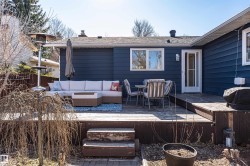 Spacious backyard deck featuring a dark wood-finish, multi-level design, and direct access to the home via a white paneled door - 