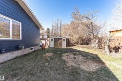 Spacious backyard featuring a storage shed with double doors and an adjacent wooden fence - 