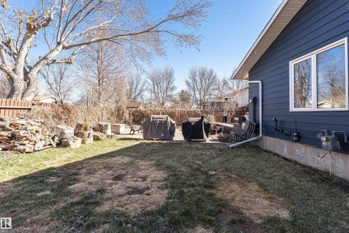 Spacious backyard featuring a manicured lawn, a large deck area, and dark blue siding with white trim - 49 Ash Crescent, St. Albert, AB - Outdoor