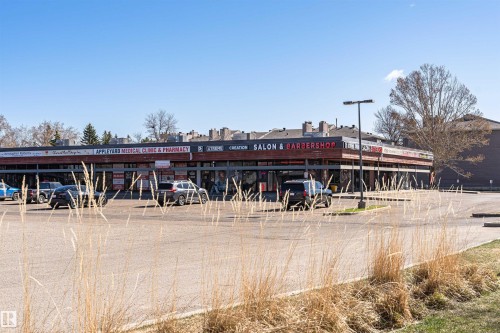 Commercial building with multiple storefronts and an expansive paved parking lot - 49 Ash Crescent, St. Albert, AB - Outdoor