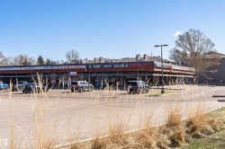 Commercial building with multiple storefronts and an expansive paved parking lot - 