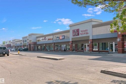 Commercial strip mall featuring multiple retail units with prominent storefronts, brick and neutral-toned facade, and a spacious parking lot - 49 Ash Crescent, St. Albert, AB - Outdoor