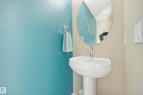 Pedestal sink with chrome faucet, paired with an oval wall mirror - 481 Sheppard Boulevard, Leduc, AB - Indoor Photo Showing Bathroom