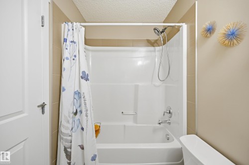 Bathtub with an integrated shower enclosure, featuring a chrome showerhead and faucet - 481 Sheppard Boulevard, Leduc, AB - Indoor Photo Showing Bathroom
