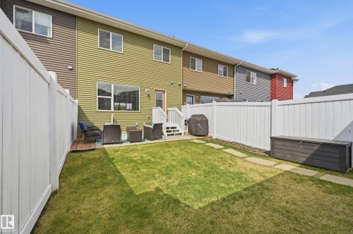 Fenced backyard with a manicured lawn, stone pathway, and a patio area featuring a composite deck section - 481 Sheppard Boulevard, Leduc, AB - Outdoor With Exterior