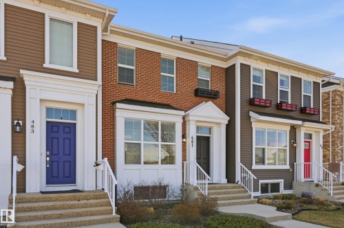 Townhome exterior featuring a blue entry door with transom window, white trim detailing, and an exterior wall lantern - 481 Sheppard Boulevard, Leduc, AB - Outdoor With Facade