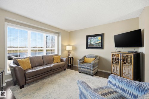 Bright living area with large window, neutral wall tones, dark wood-finish flooring, and recessed ceiling lights - 481 Sheppard Boulevard, Leduc, AB - Indoor Photo Showing Living Room