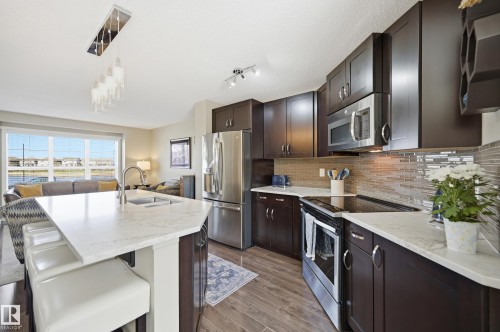 Kitchen featuring dark wood cabinetry, stainless steel appliances, a tile backsplash, and light-toned countertops - 481 Sheppard Boulevard, Leduc, AB - Indoor Photo Showing Kitchen With Upgraded Kitchen