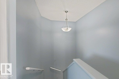 Interior space featuring light blue walls, a white ceiling with a textured finish, and a pendant light fixture - 3347 24 Avenue, Edmonton, AB - Indoor