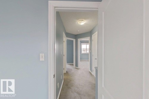 The property features a hallway with light blue walls and neutral-toned carpeting - 3347 24 Avenue, Edmonton, AB - Indoor Photo Showing Other Room