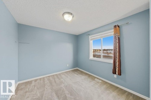 This room features light blue walls, a window offering natural light, and a textured ceiling - 3347 24 Avenue, Edmonton, AB - Indoor Photo Showing Other Room