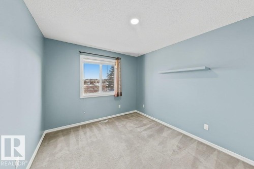 This room features light blue walls, gray carpet, a white ceiling with a recessed light, and a window with a dark frame and blinds - 3347 24 Avenue, Edmonton, AB - Indoor Photo Showing Other Room