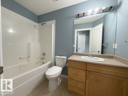 Well-appointed bathroom featuring a combination bathtub and shower, a single vanity with an oval sink, and a large wall-mounted mirror - 3347 24 Avenue, Edmonton, AB - Indoor Photo Showing Bathroom
