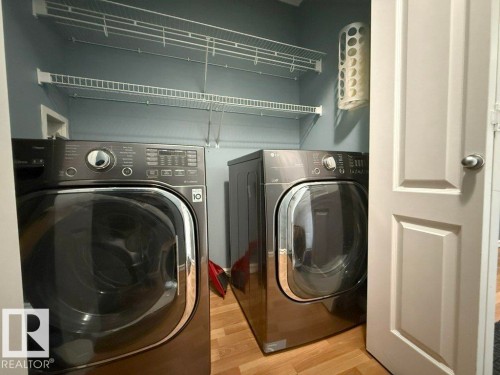 The laundry area features a washer and dryer, wire shelving, and wood-look flooring - 3347 24 Avenue, Edmonton, AB - Indoor Photo Showing Laundry Room
