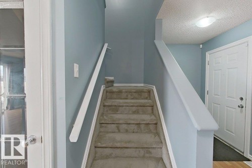 Staircase featuring carpeted steps, a white handrail, and light blue walls - 3347 24 Avenue, Edmonton, AB - Indoor Photo Showing Other Room
