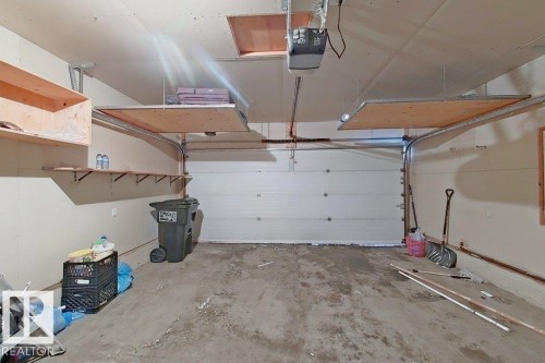 The property features an attached garage with a concrete floor, equipped with shelving units and overhead storage solutions - 3347 24 Avenue, Edmonton, AB - Indoor Photo Showing Garage