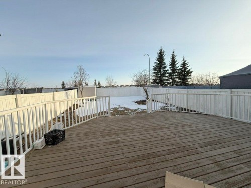 The property features a wooden deck with white railings, overlooking a fenced yard - 3347 24 Avenue, Edmonton, AB - Outdoor