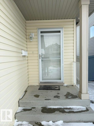 The property features a front entrance with a storm door, concrete steps, and a sheltered porch area - 3347 24 Avenue, Edmonton, AB - Outdoor With Exterior