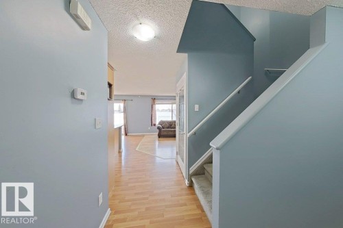 Inviting entrance foyer with light blue walls, a staircase with carpeted treads, and wood flooring extending into the main living area - 3347 24 Avenue, Edmonton, AB - Indoor Photo Showing Other Room