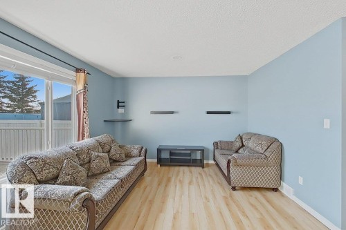 Living area featuring light-colored flooring, light blue walls, and a large window providing views of the outdoors - 3347 24 Avenue, Edmonton, AB - Indoor Photo Showing Living Room