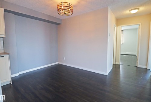Open concept living space featuring dark wood-finish flooring, a modern drum chandelier, and a neutral color palette - 901 10160 116 Street, Edmonton, AB - Indoor Photo Showing Other Room