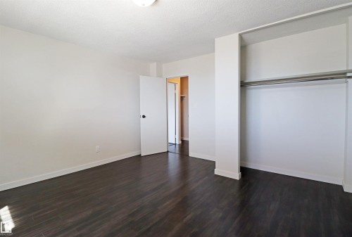 Spacious room with dark wood-finish flooring, white baseboards, and a neutral wall palette - 901 10160 116 Street, Edmonton, AB - Indoor Photo Showing Other Room