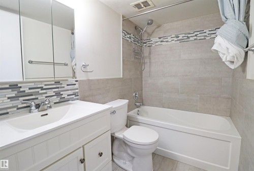 Bathroom featuring a white vanity with integrated sink, chrome faucet, and a mosaic tile backsplash - 901 10160 116 Street, Edmonton, AB - Indoor Photo Showing Bathroom