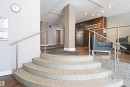 Entryway featuring curved tiled stairs with stainless steel handrails, wood-finish flooring, a stainless steel elevator, and a textured wood-panel accent wall - 901 10160 116 Street, Edmonton, AB  - Indoor Photo Showing Other Room 