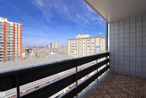 Balcony featuring wood-finish tile flooring, a dark-toned railing, and a light-toned tiled exterior wall - 901 10160 116 Street, Edmonton, AB -  With Exterior