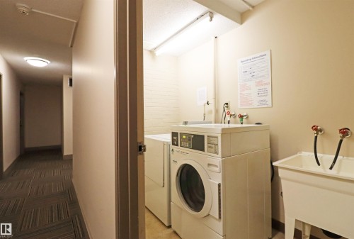 Dedicated laundry room featuring a washer, dryer, utility sink, and wall-mounted operating instructions - 901 10160 116 Street, Edmonton, AB - Indoor Photo Showing Laundry Room