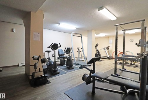 Fitness center featuring wood-finish flooring, fluorescent lighting, and neutral-toned walls - 901 10160 116 Street, Edmonton, AB - Indoor Photo Showing Gym Room