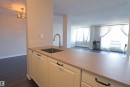 Kitchen counter featuring a stainless steel sink, gooseneck faucet, light-colored countertop, white shaker-style cabinetry with dark hardware, and a subway tile backsplash - 901 10160 116 Street, Edmonton, AB  - Indoor Photo Showing Kitchen 