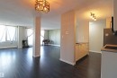 Open-concept living space featuring dark wood-finish flooring, multiple windows with white window treatments, and a decorative ceiling light fixture - 901 10160 116 Street, Edmonton, AB  - Indoor 
