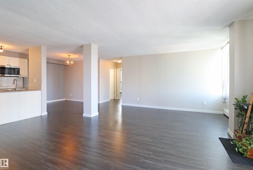 Open-concept living area featuring wood-finish flooring, light neutral wall paint, and white trim - 901 10160 116 Street, Edmonton, AB - Indoor Photo Showing Kitchen