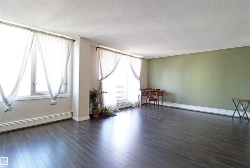 Spacious room featuring dark wood-finish flooring and a light green accent wall - 901 10160 116 Street, Edmonton, AB - Indoor