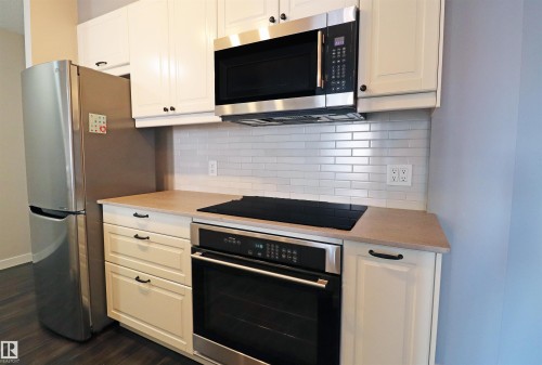 Modern kitchen area featuring stainless steel appliances including a refrigerator, built-in oven, and microwave - 901 10160 116 Street, Edmonton, AB - Indoor Photo Showing Kitchen