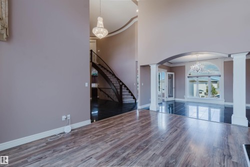 Spacious interior featuring wood-finish flooring, a grand curved staircase, and an arched entryway - 2408 Tegler Green, Edmonton, AB - Indoor Photo Showing Other Room